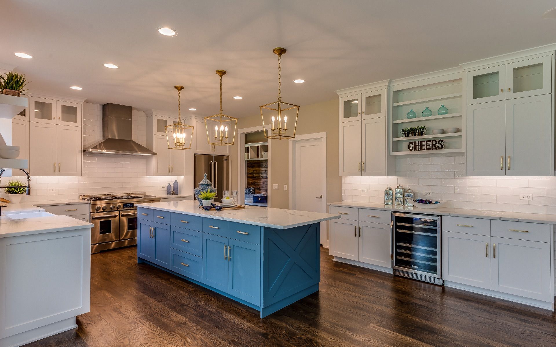 Bright modern kitchen with blue island, white cabinets, stainless appliances, and marble countertops
