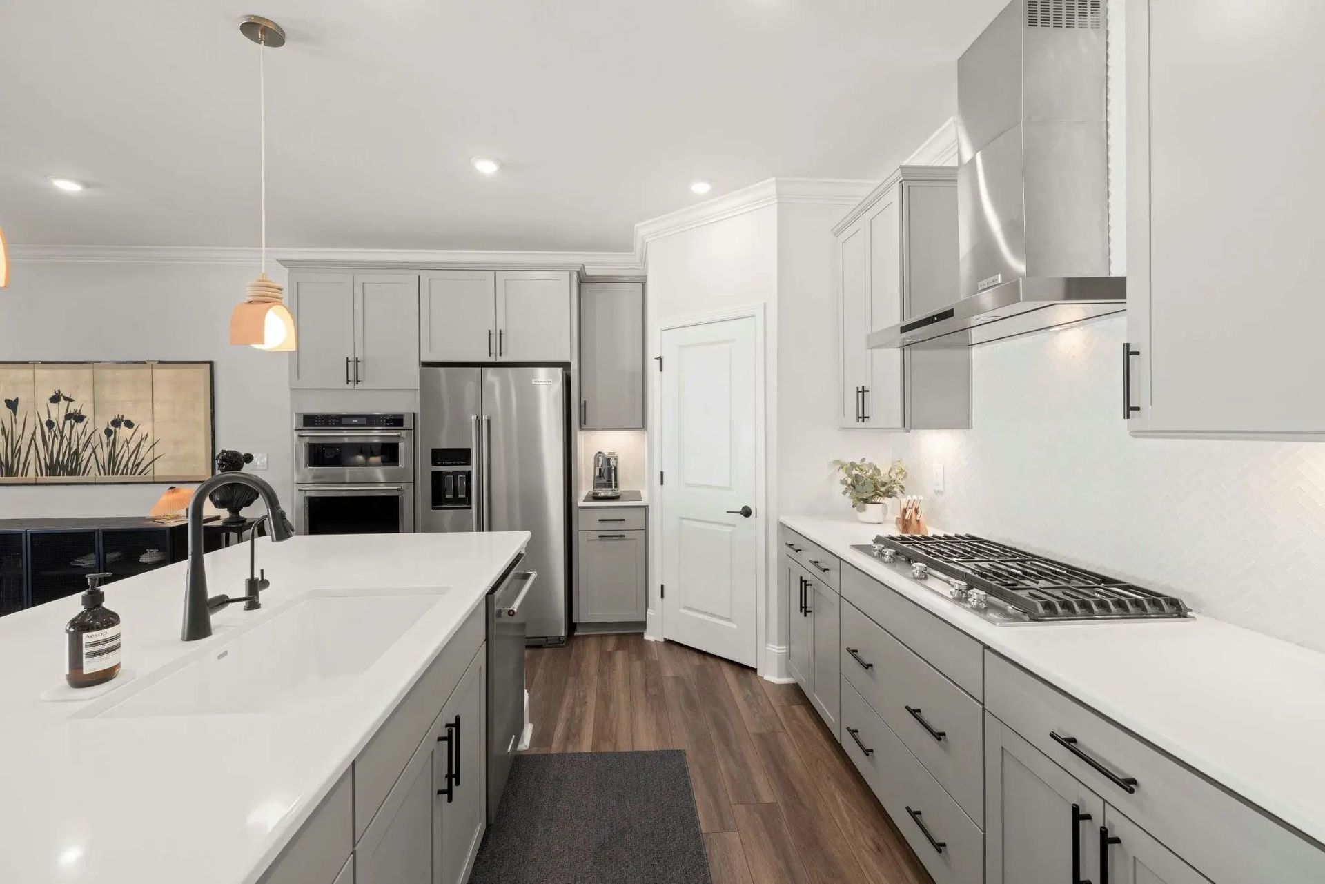Bright modern kitchen with white cabinets, gray island, stainless steel appliances, and wood floors