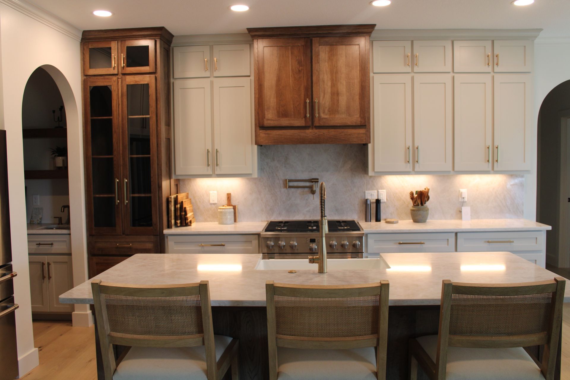 Modern kitchen with white cabinets, wood accents, and a long island with three stools