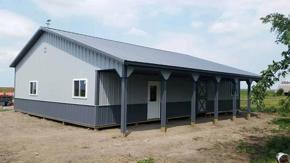 Gray and blue metal building with a covered porch under a cloudy sky.