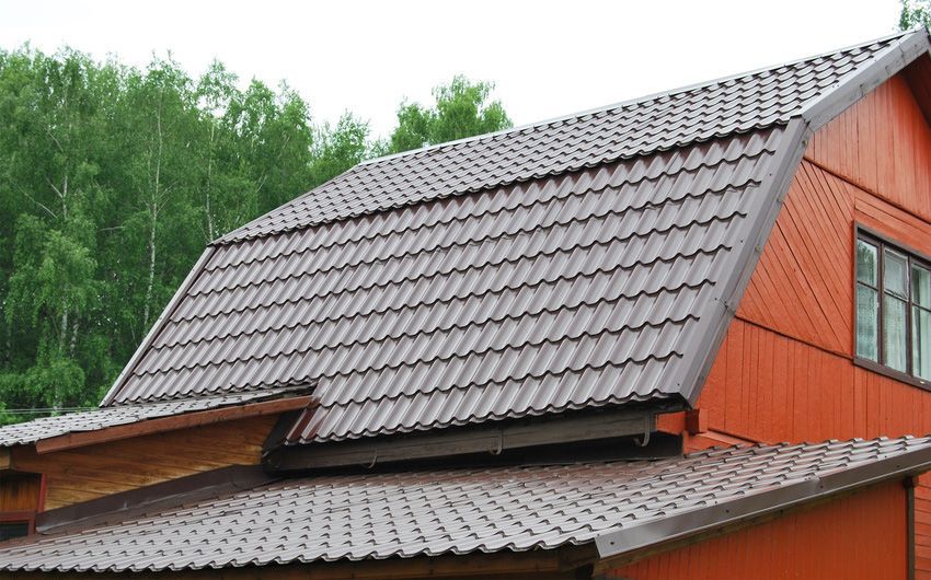 A red house with a brown roof and trees in the background.