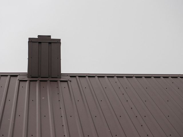 A brown metal roof with a chimney on top of it.