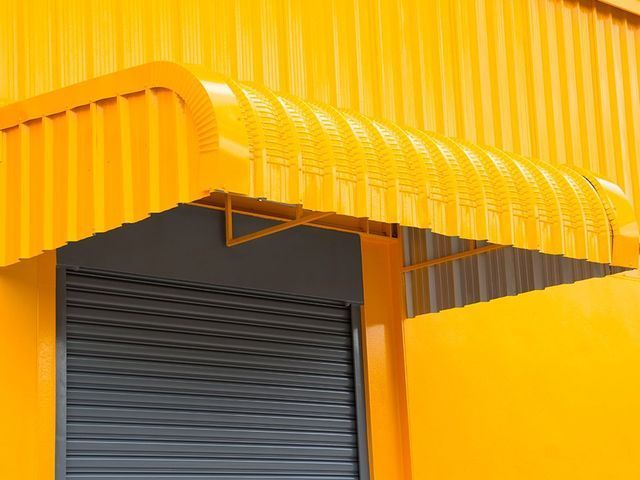 A yellow building with a canopy over a garage door.