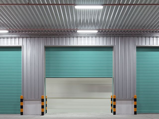 A warehouse with green roller shutters on the doors.