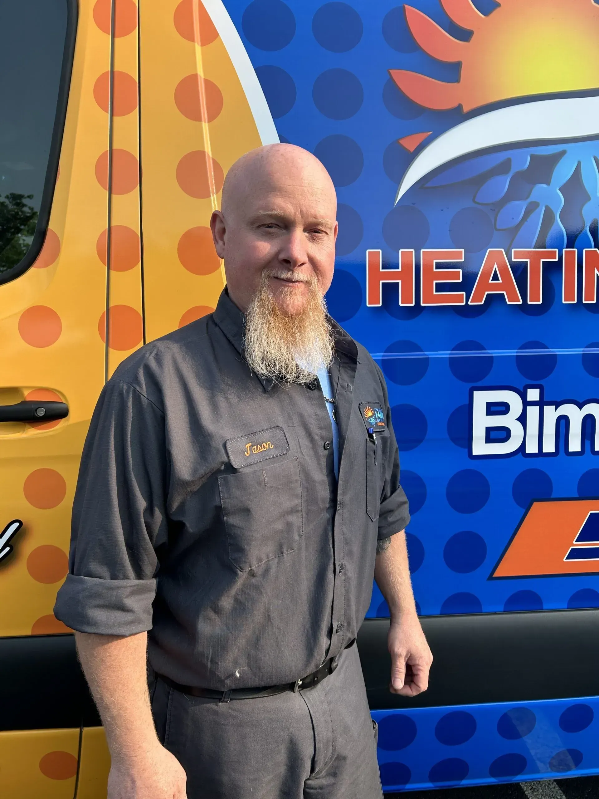 Man standing beside a colorful heating service van with blue and orange graphics
