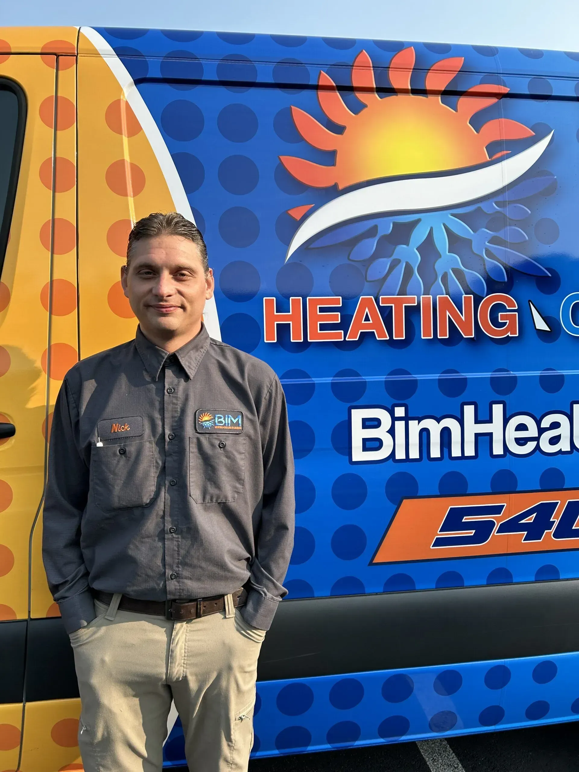 Man standing beside a blue heating company van with sun logo and BimHeating branding