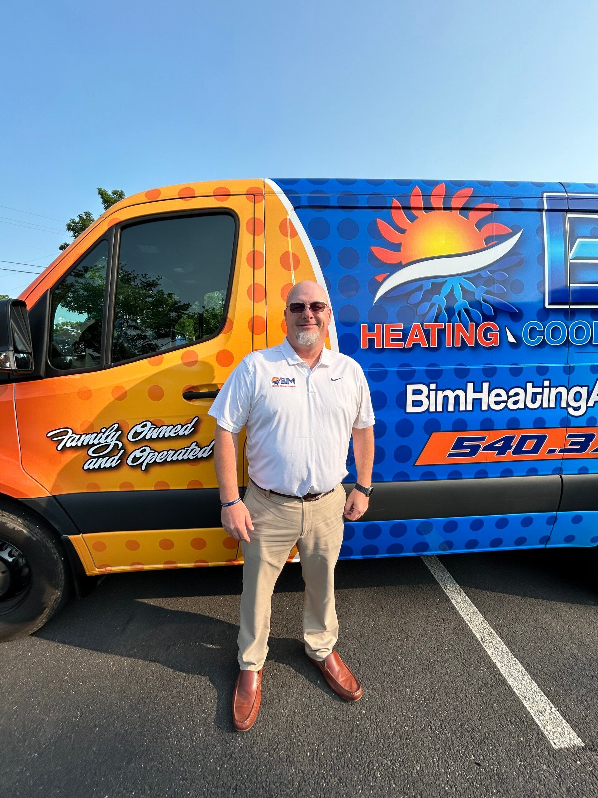 Man standing beside a branded heating and cooling service van in a parking lot