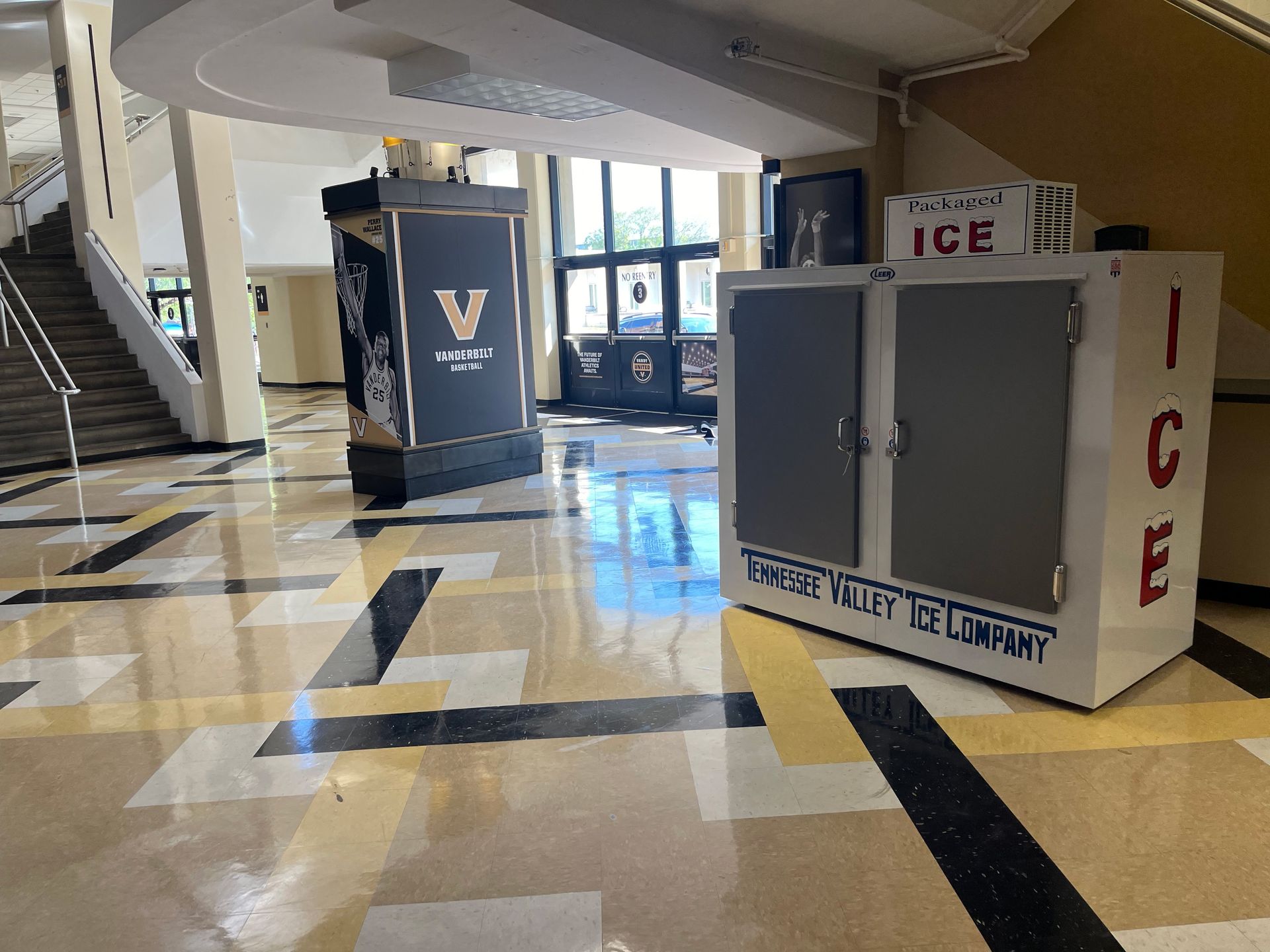 Hallway with ice machine and display, black, gold, and white floor, and stairs.