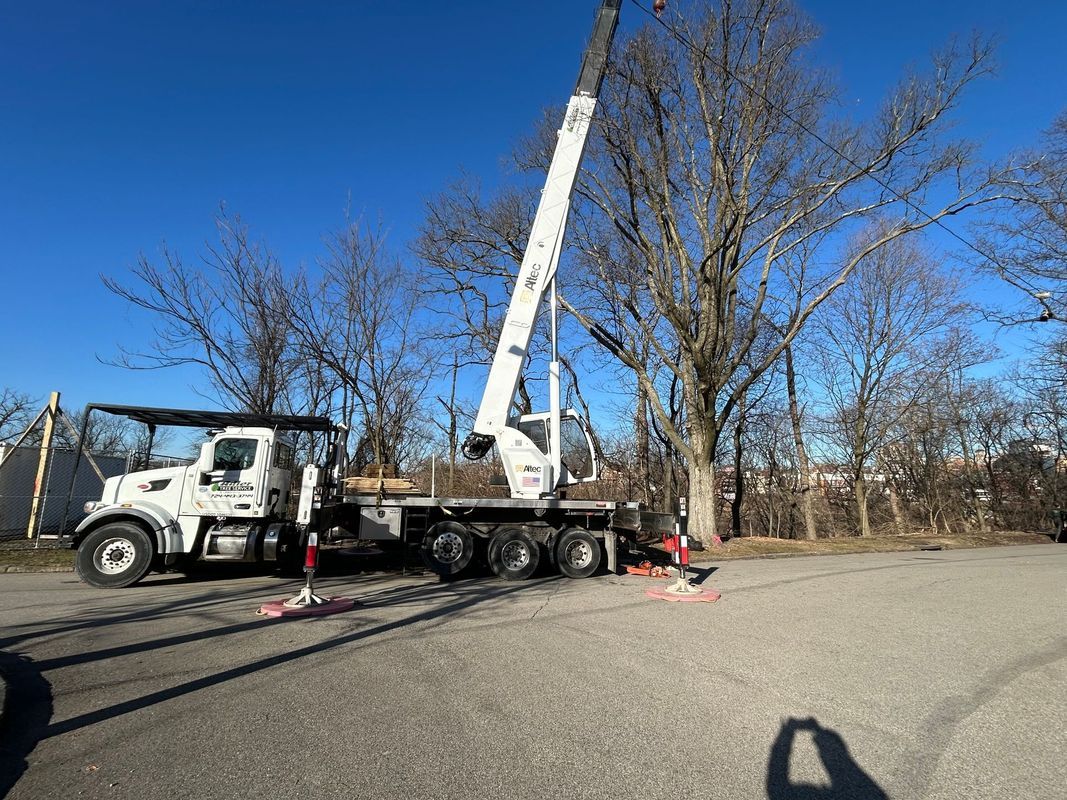 A white truck with a crane attached to it is parked in a parking lot.
