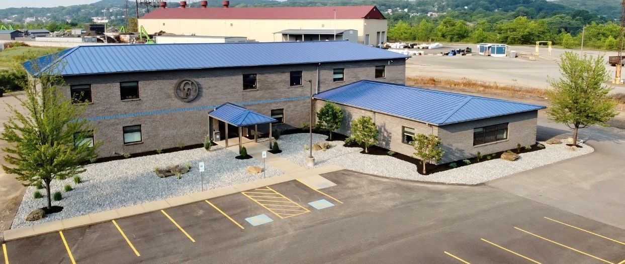 An aerial view of a building with a blue roof and a parking lot in front of it.
