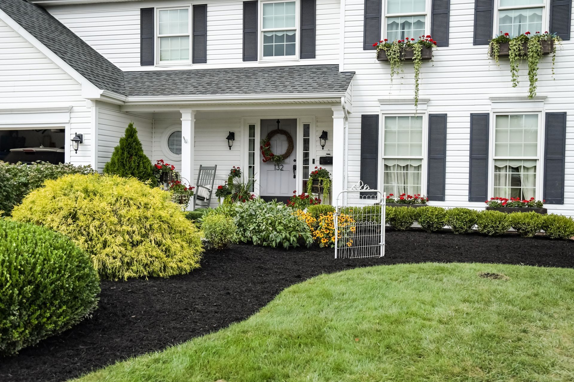 A white house with black shutters and a lush green lawn