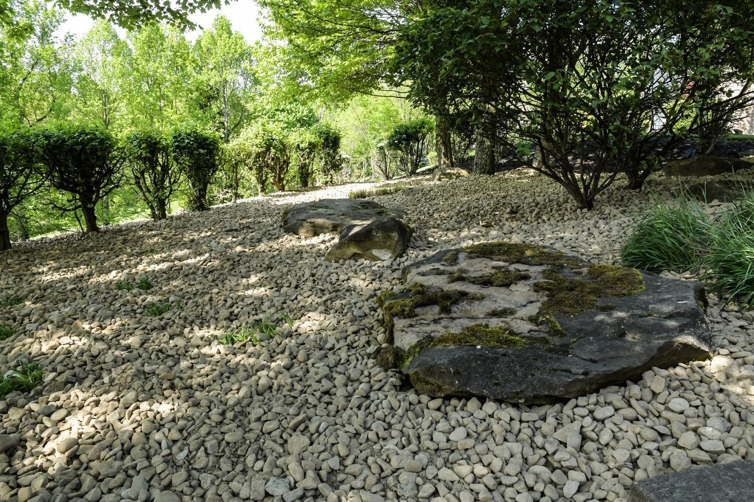 A pile of rocks in a park with trees in the background.