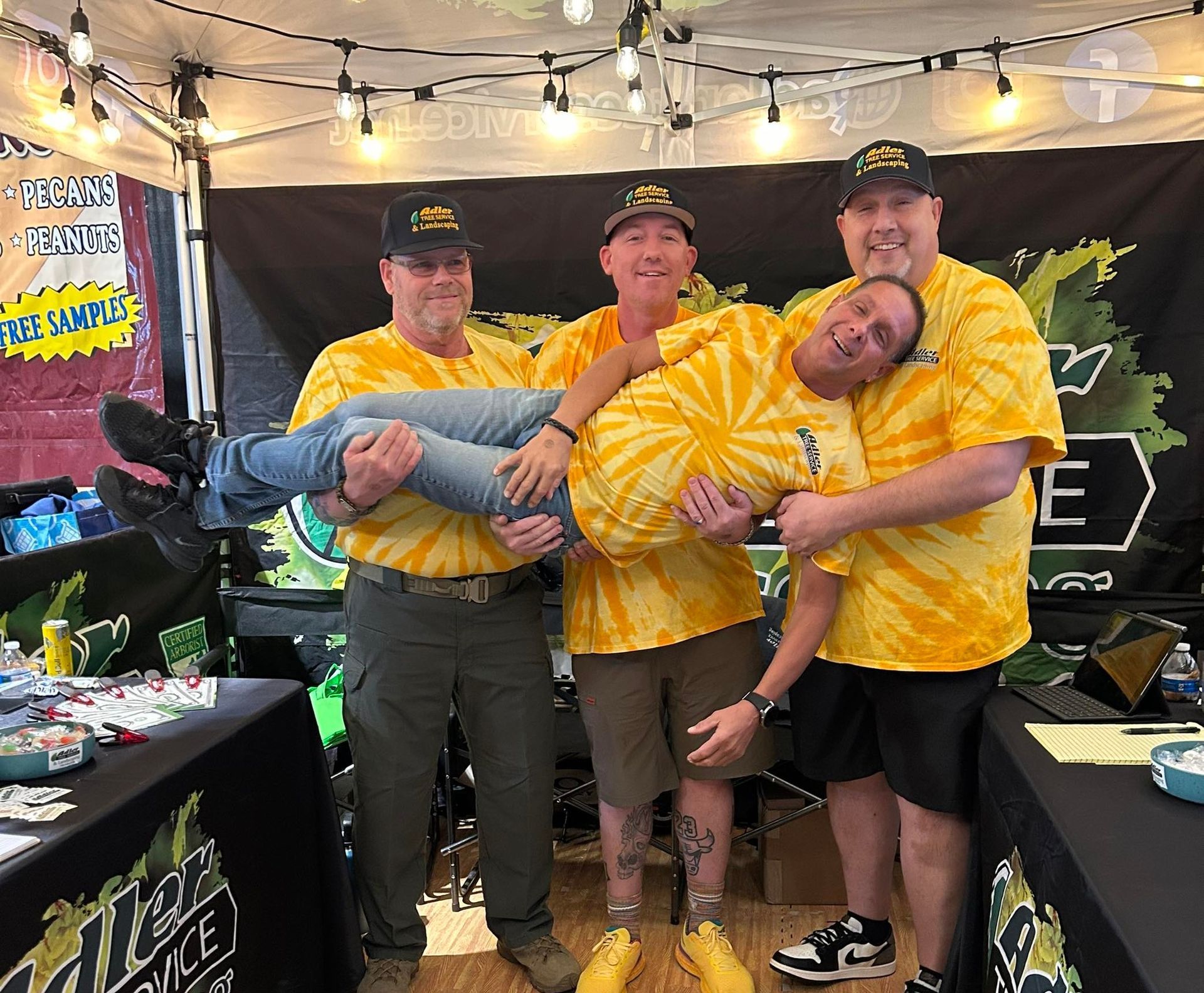 A group of men wearing yellow tie dye shirts are posing for a picture.