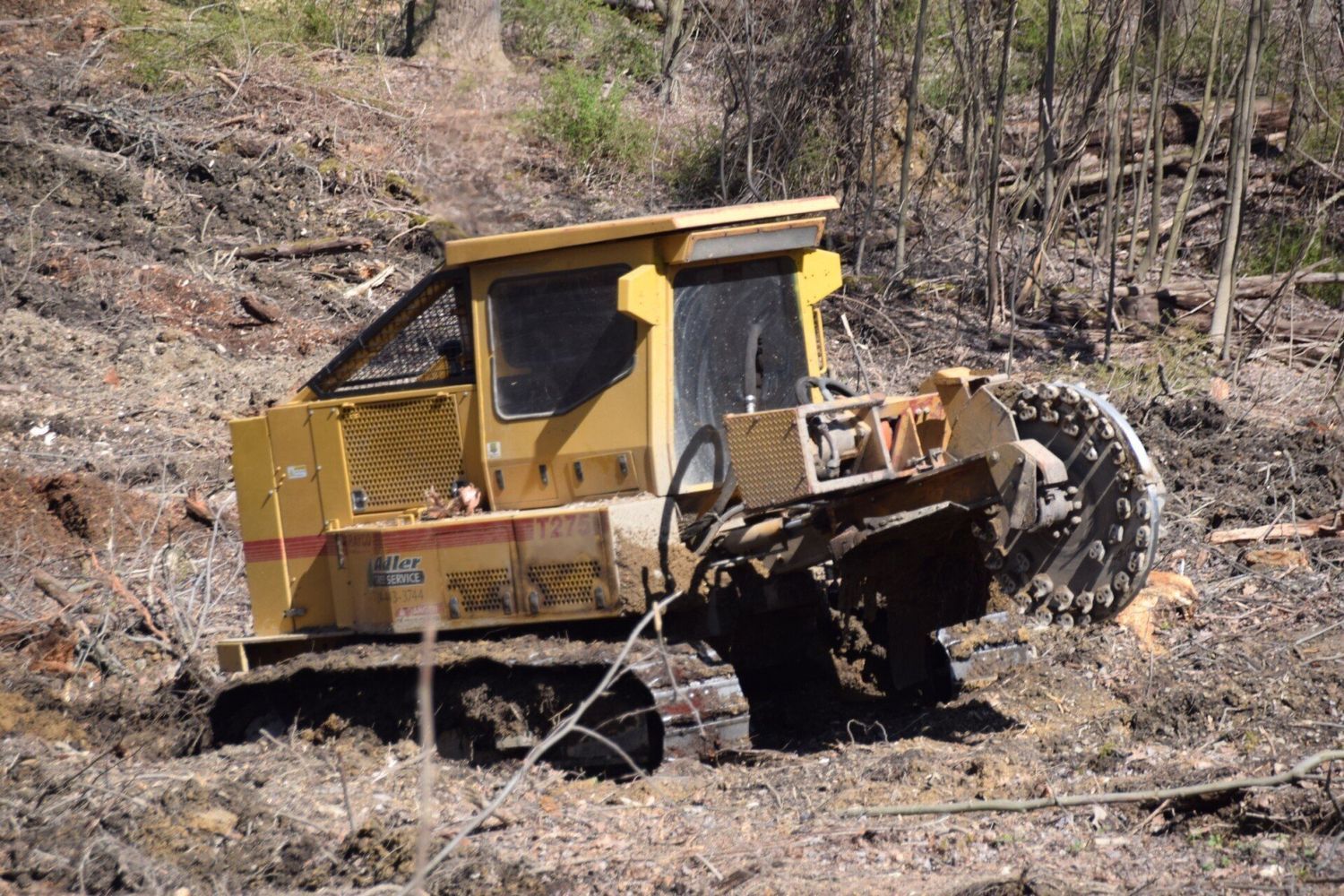 A yellow bulldozer is sitting in the middle of a dirt field.