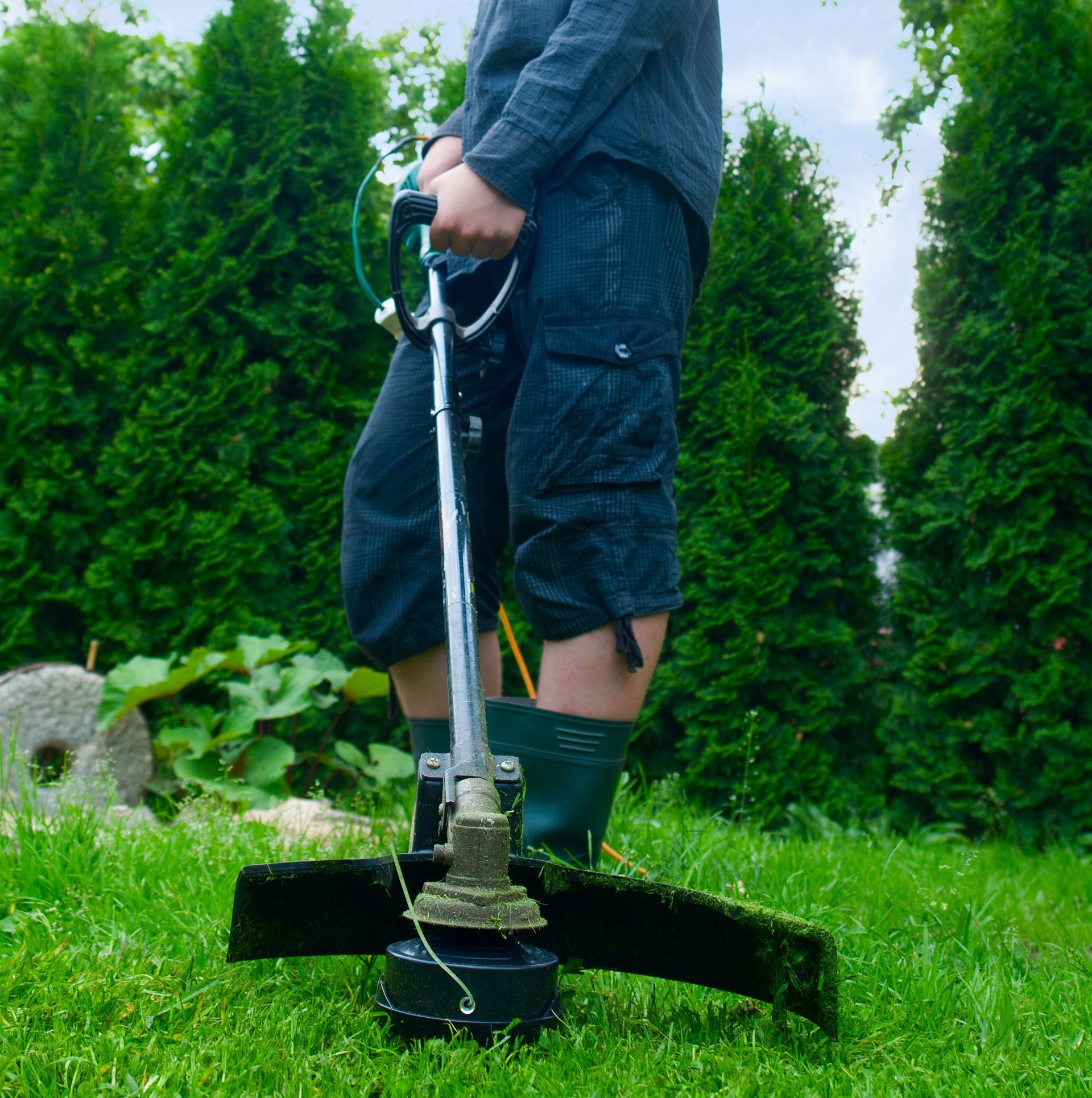 A man is using a lawn mower in the grass