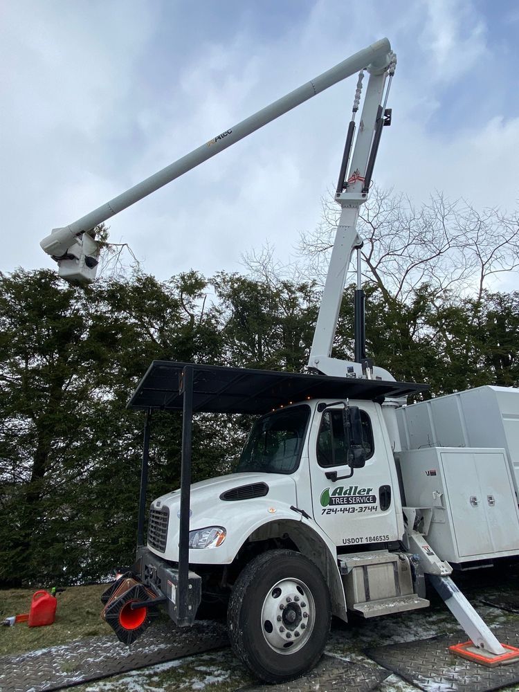 A white truck with a crane on top of it is parked on the side of the road.
