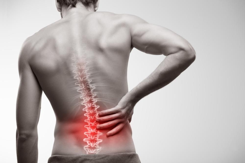 Person clutching lower back with red highlighted pain in the spine area