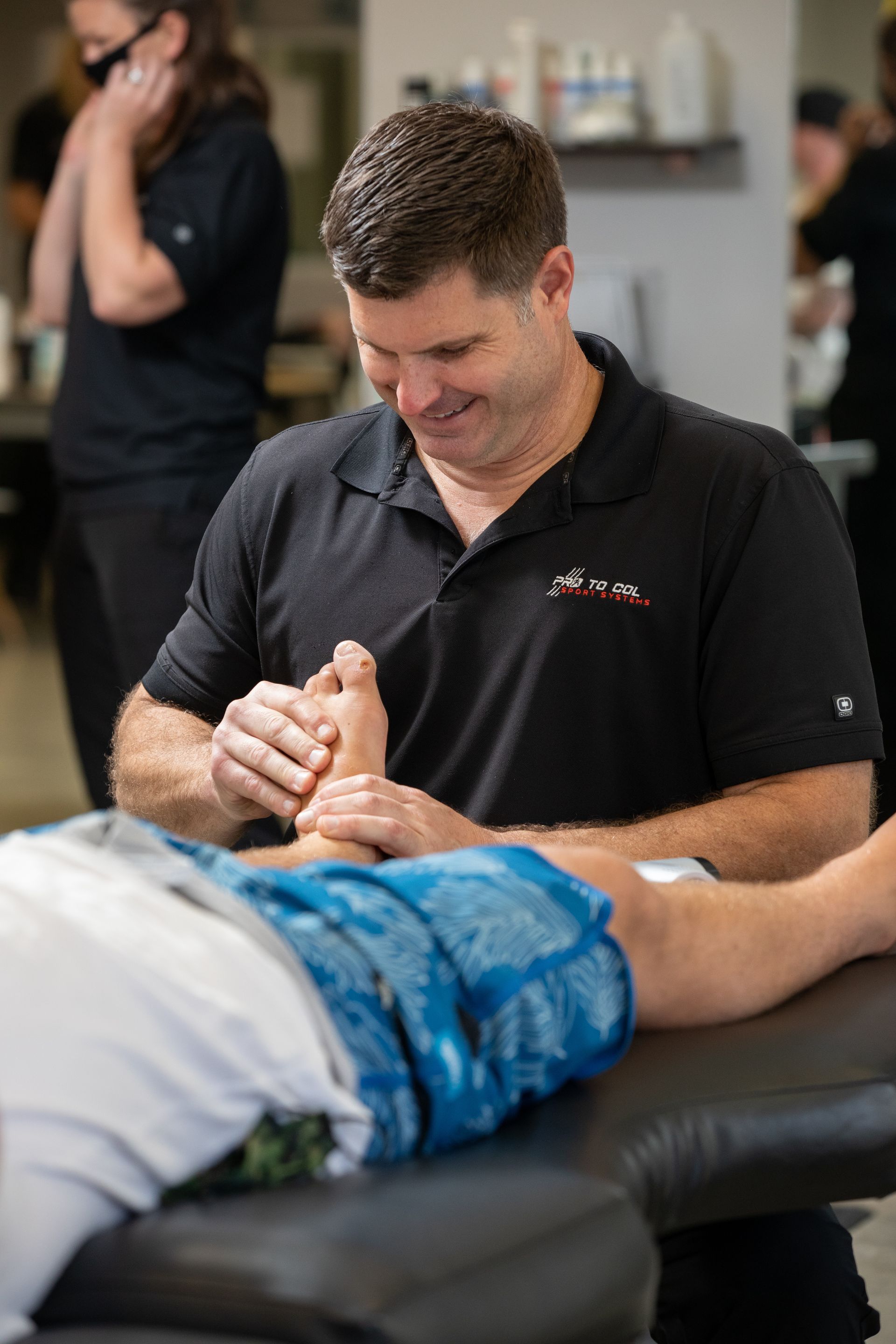 Therapist working on a patient’s leg in a clinic, with blue bandage wrapped around the knee.