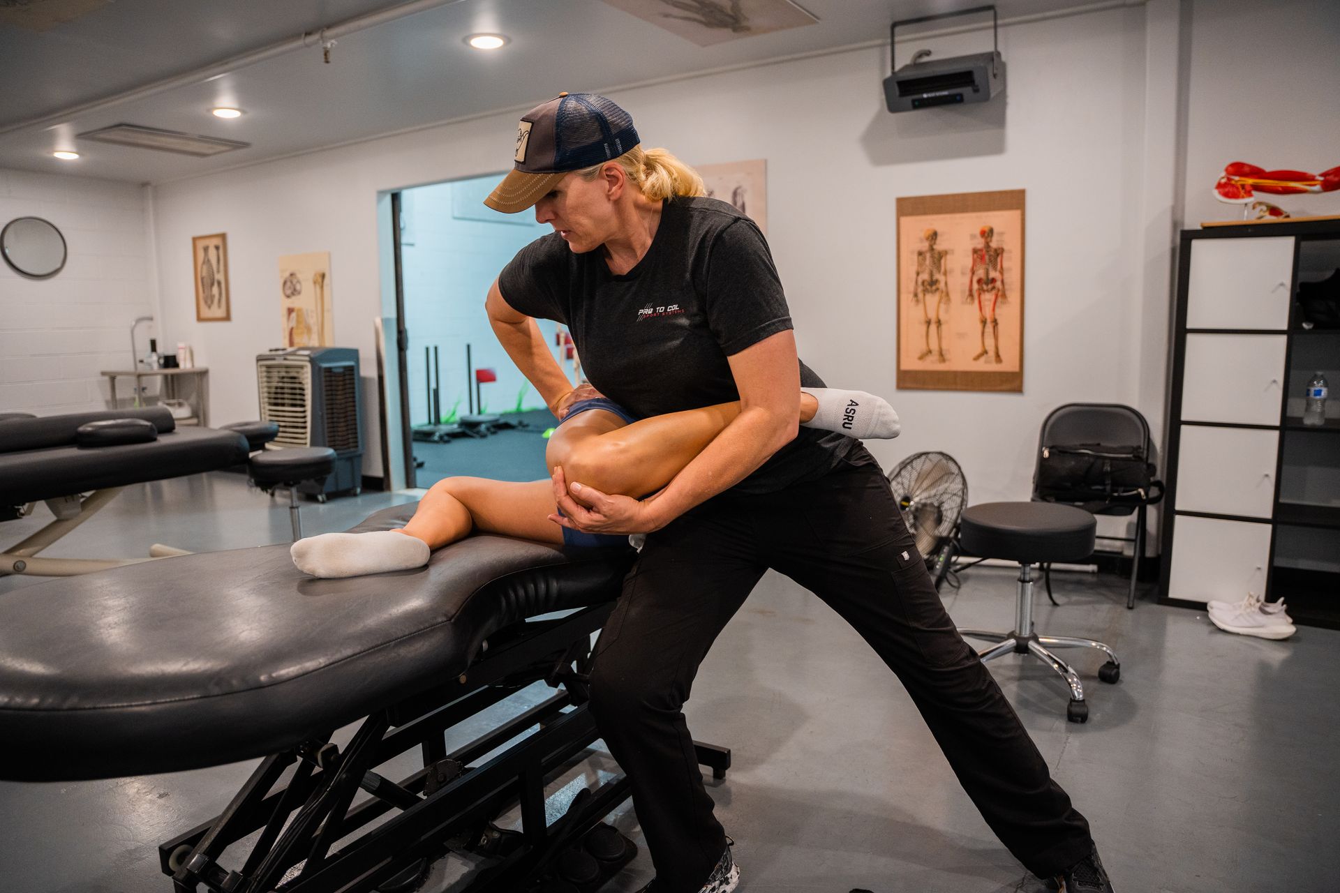 Physical therapist stretching a client’s leg on a treatment table in a clinic room