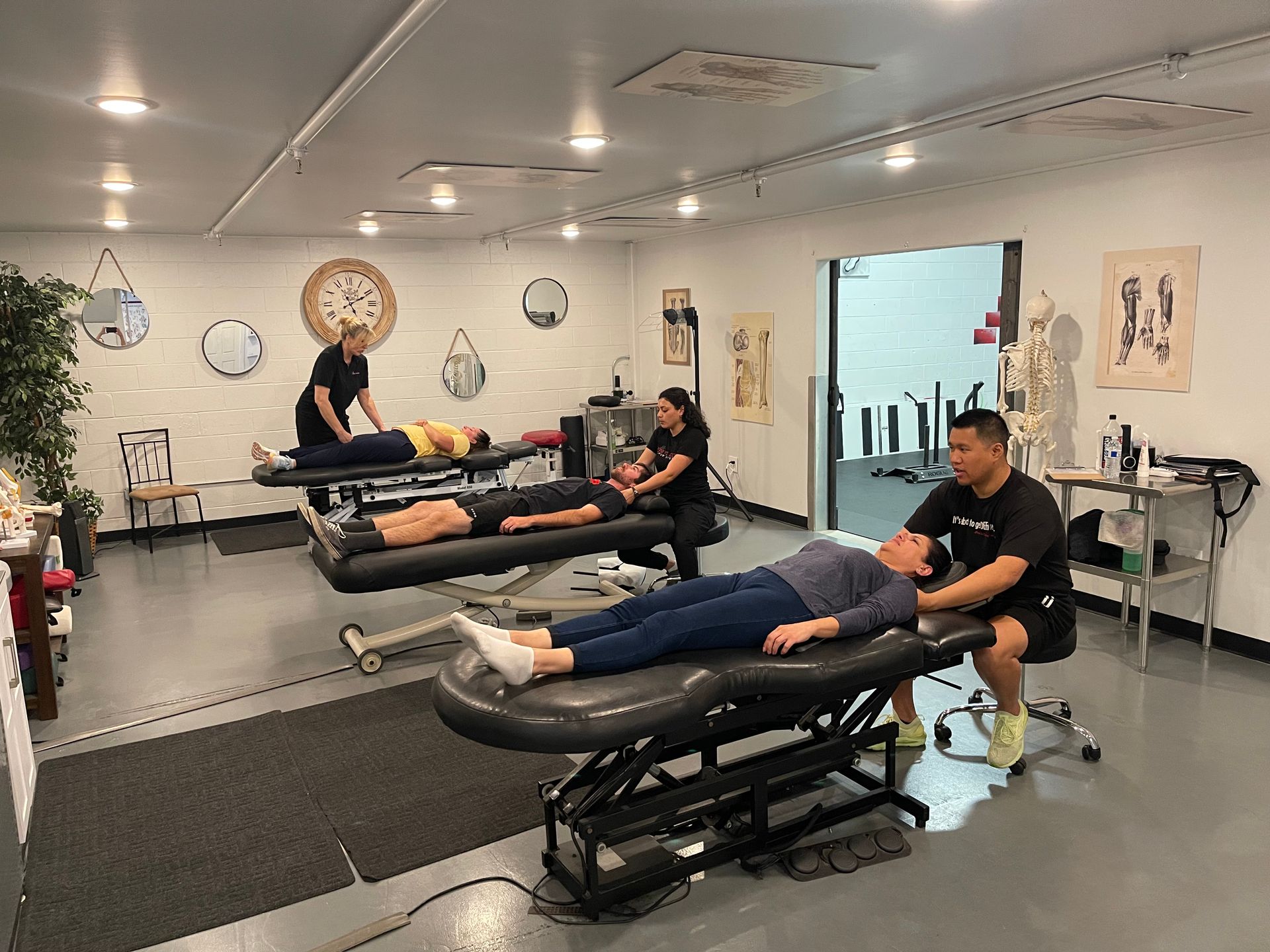 Massage studio with clients lying on treatment tables while staff work nearby