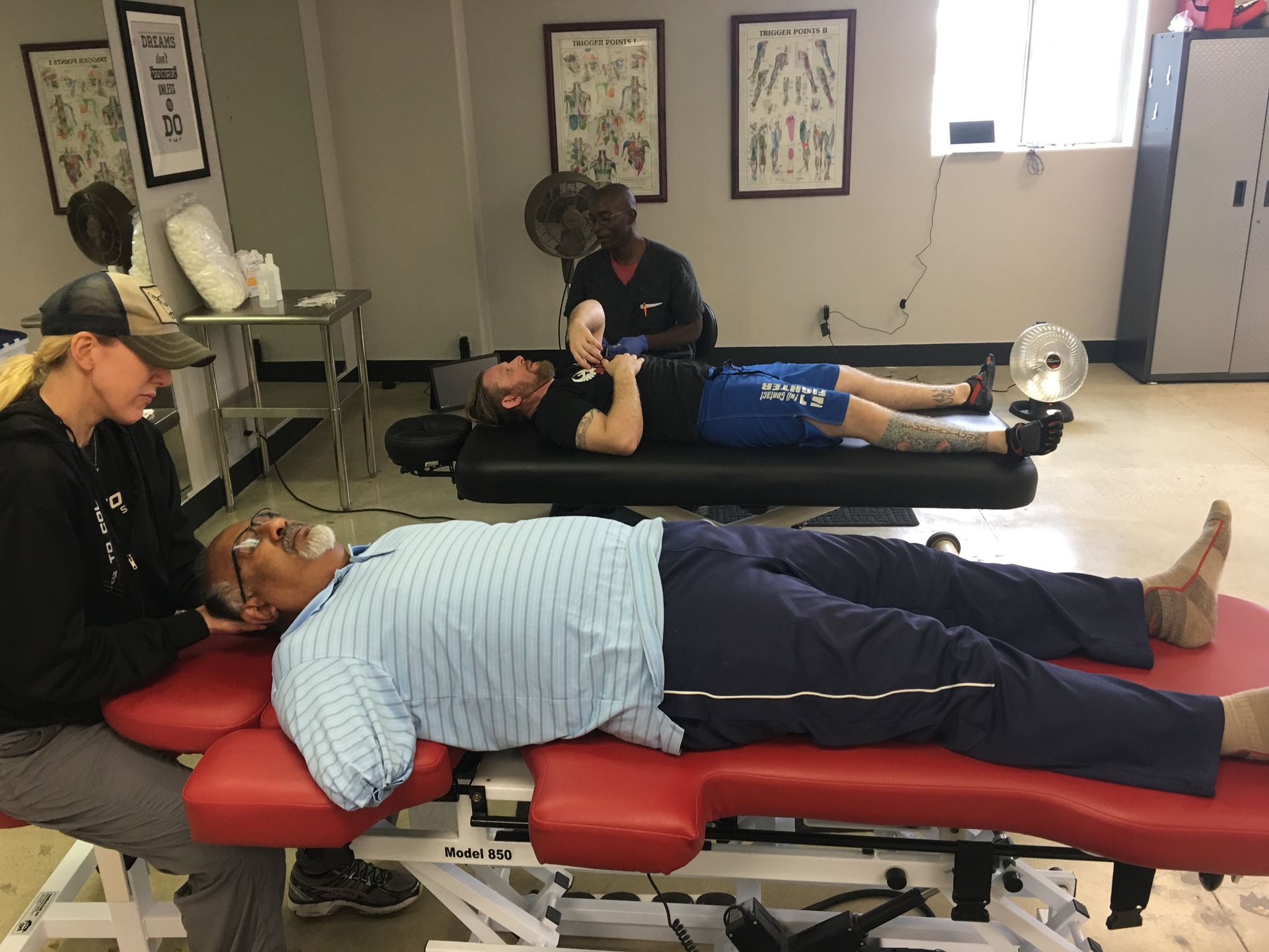 People lying on massage tables during a therapy or training session in a clinic room