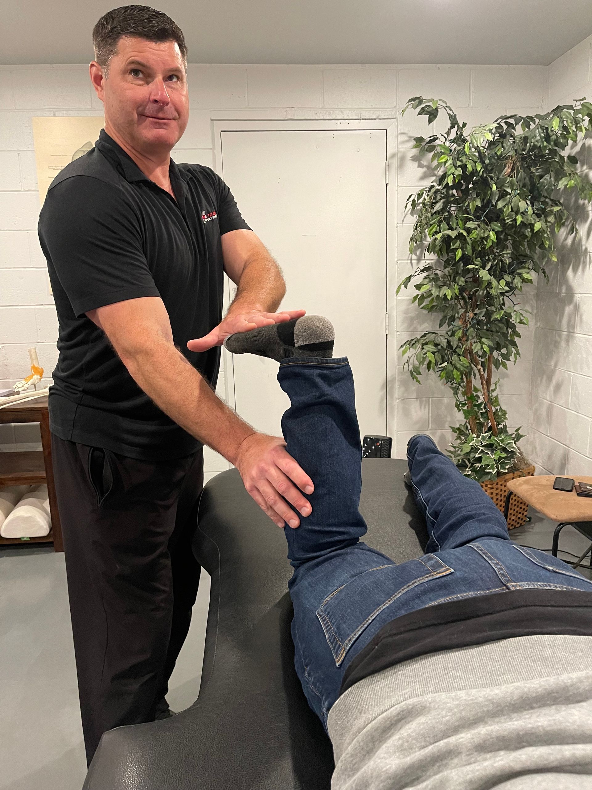 Chiropractor adjusting a patient’s leg on a treatment table in a clinic room