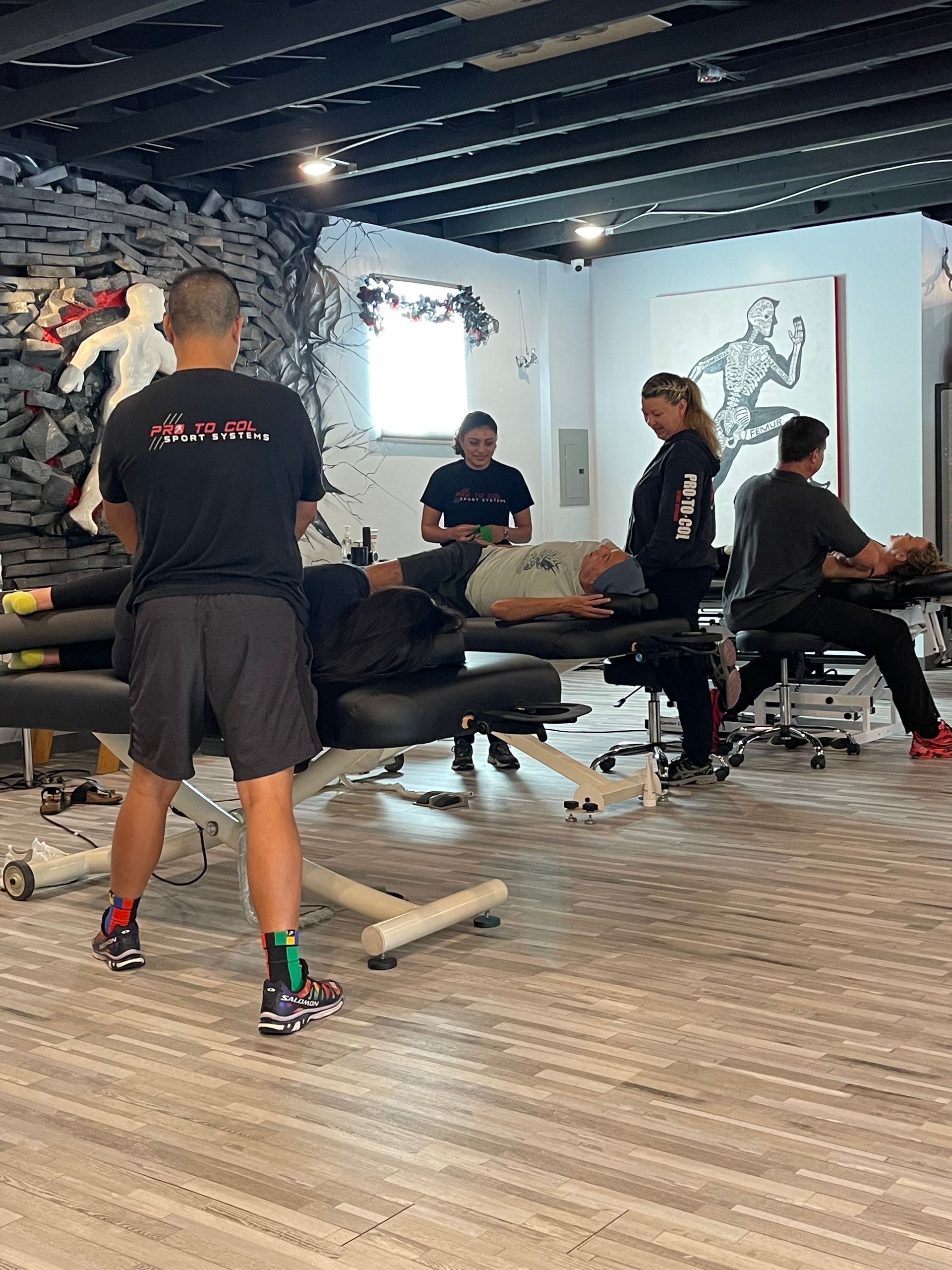 Massage therapy session in a bright studio with clients on tables and therapists working around them