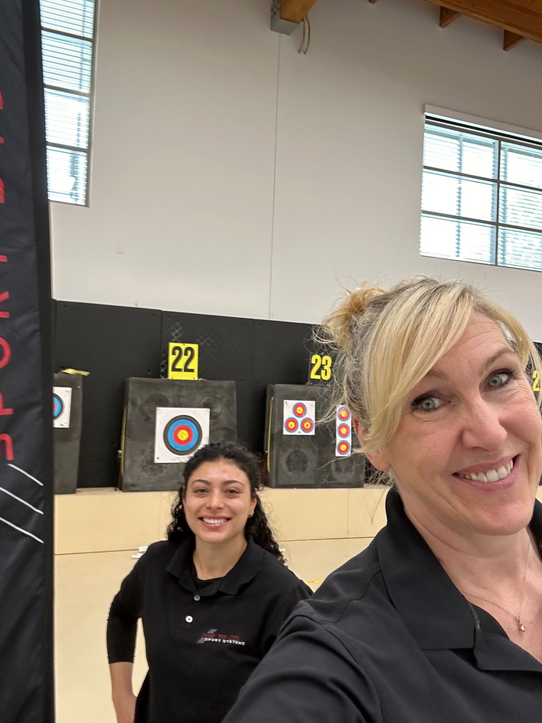 Two smiling people in a shooting range with target boards behind them