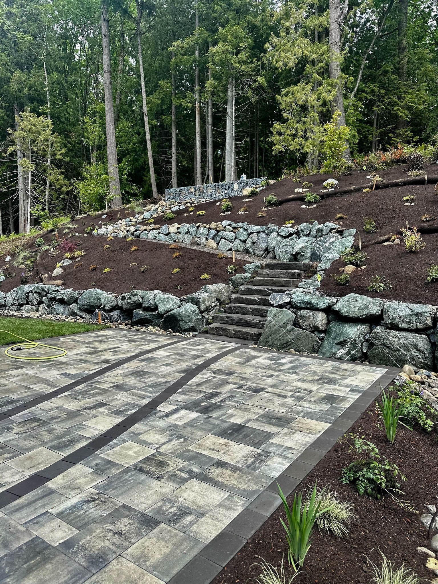 Stone patio with steps leading up a hillside garden.