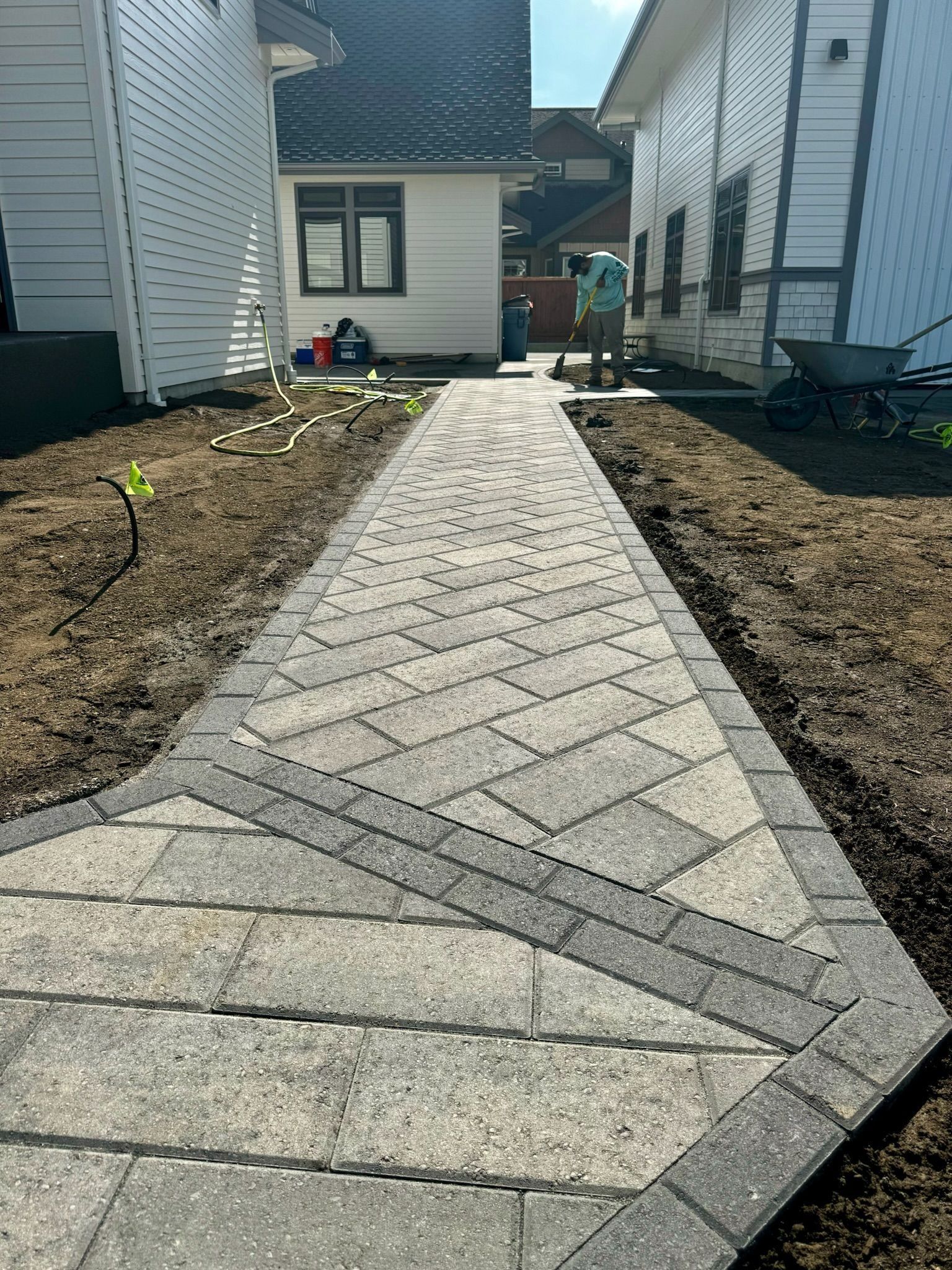 Brick pathway between two houses. A person works in the distance.