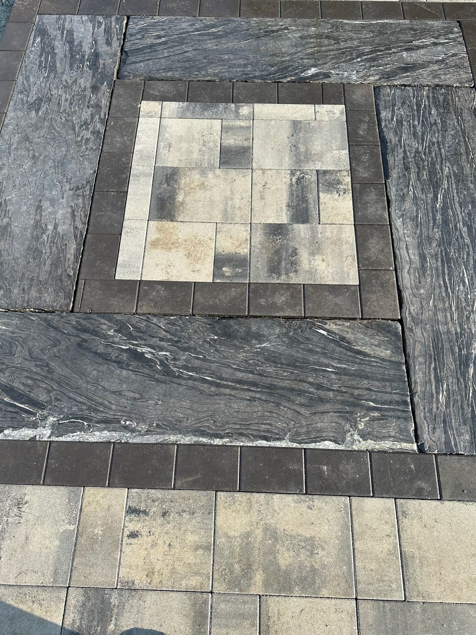 Patterned stone patio with a central square surrounded by contrasting borders and rectangles.