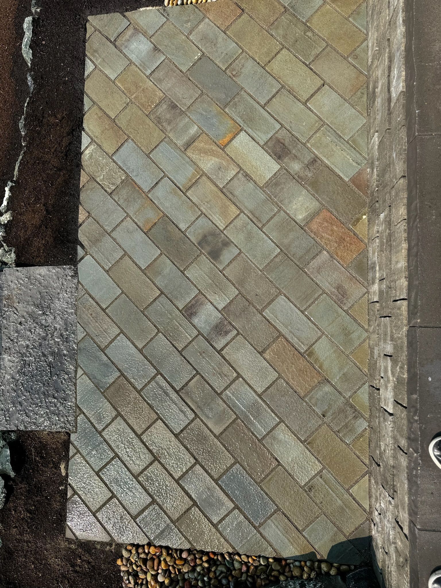 Overhead view of a section of a roof with diagonal gray shingles.