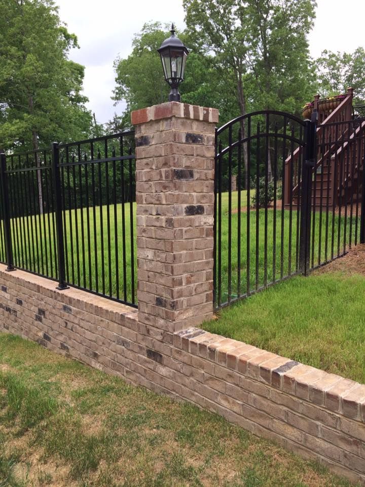 A brick wall with a metal fence surrounding it