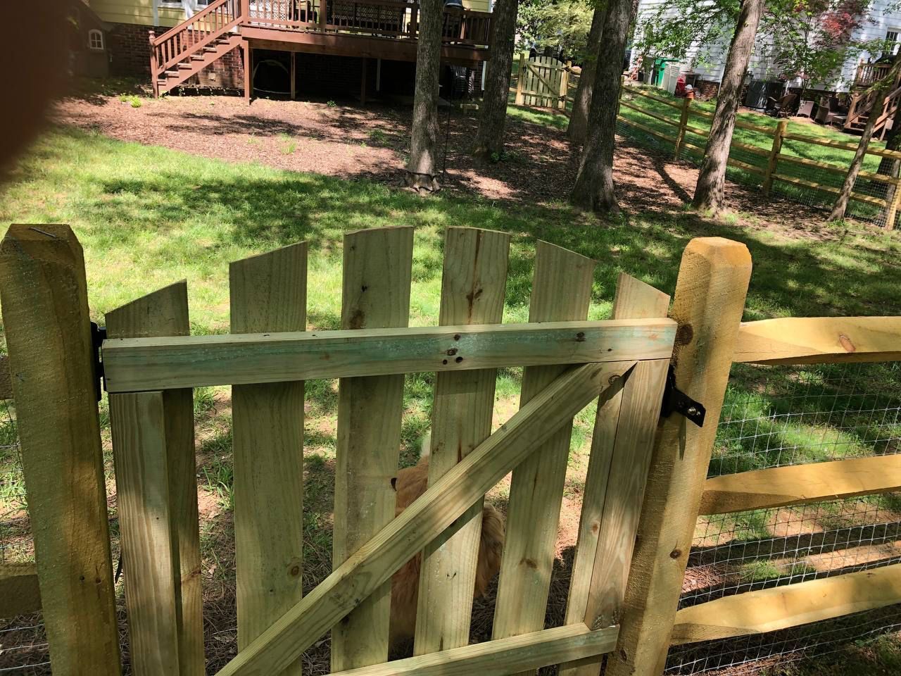 A wooden fence with a gate in front of a house.