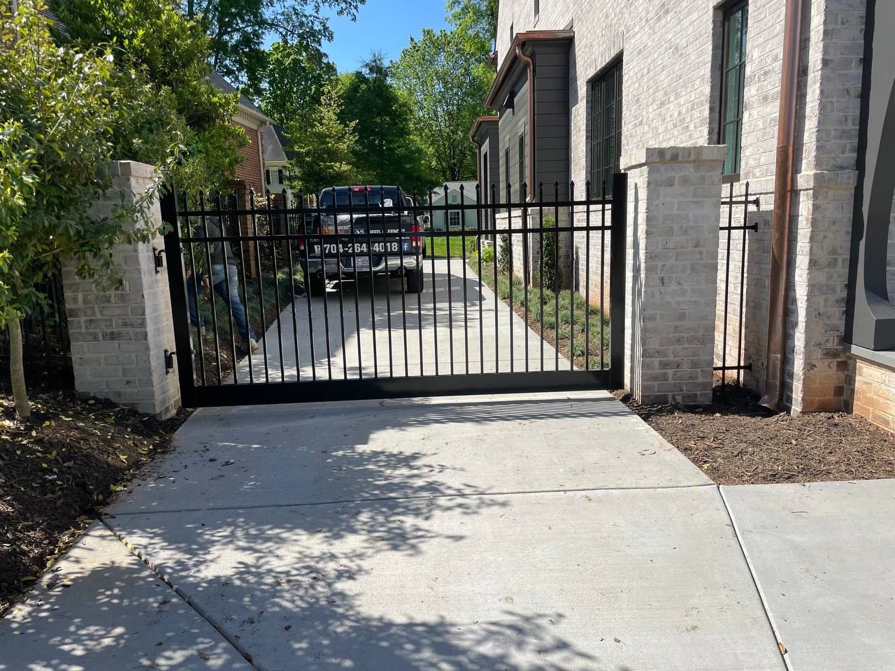 A car is parked in a driveway next to a metal gate.