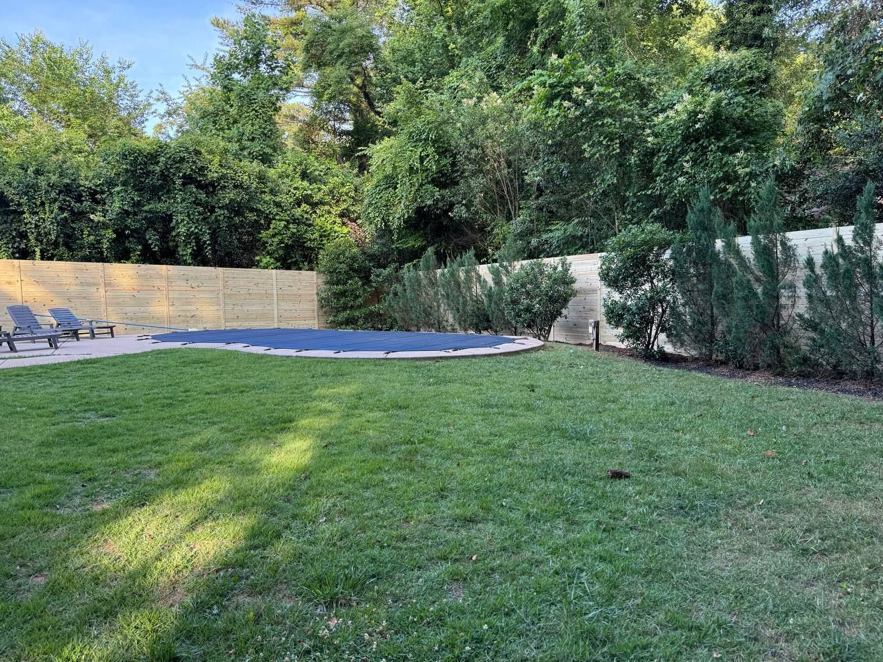 A large lush green lawn with a swimming pool in the background.