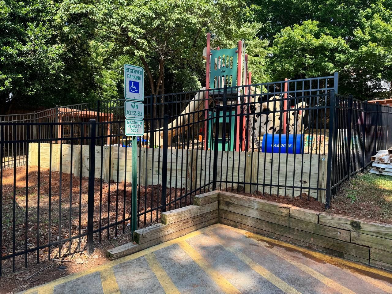 There is a handicapped parking spot in front of a playground.