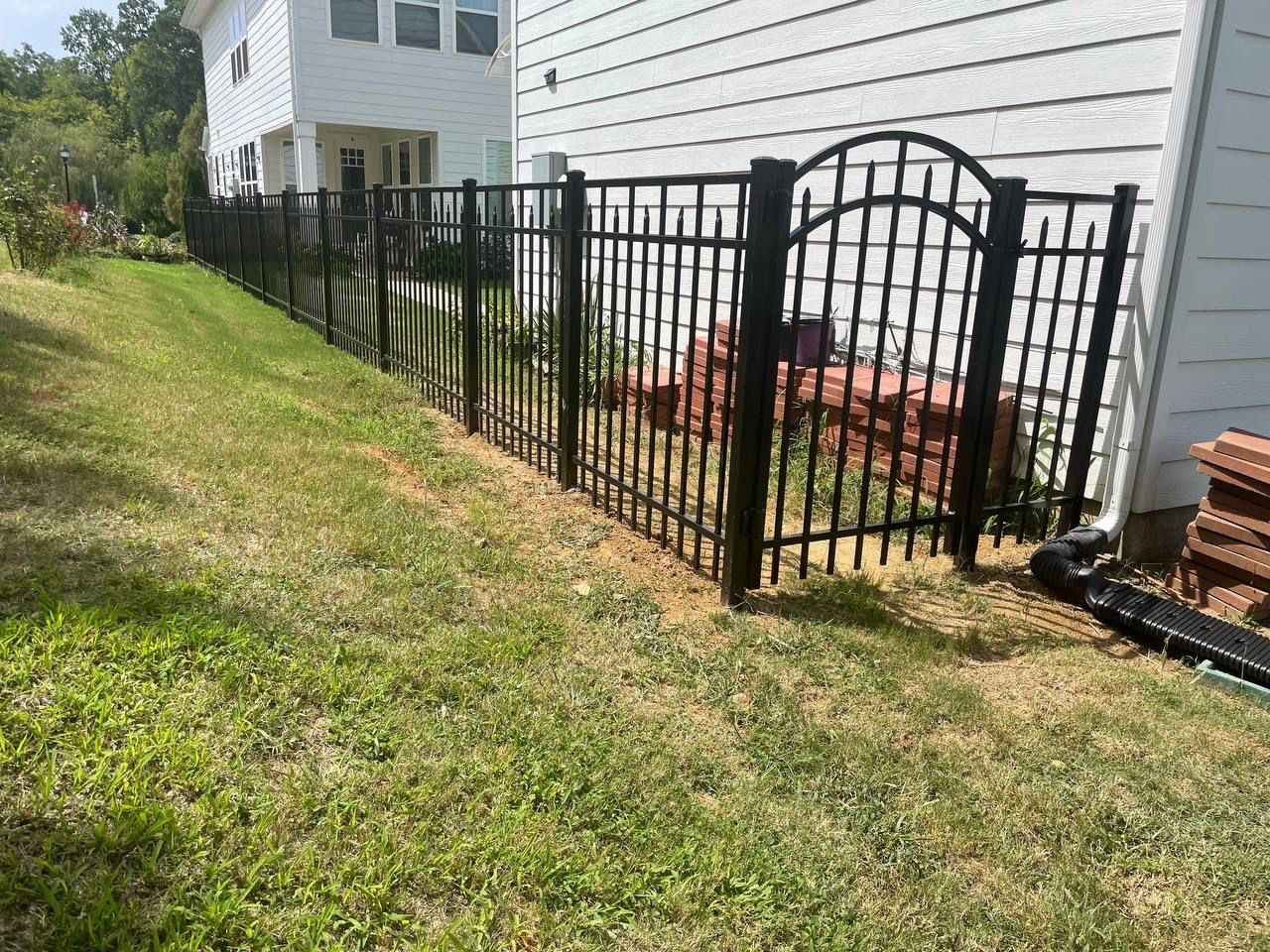 A black fence with a gate in front of a white house.