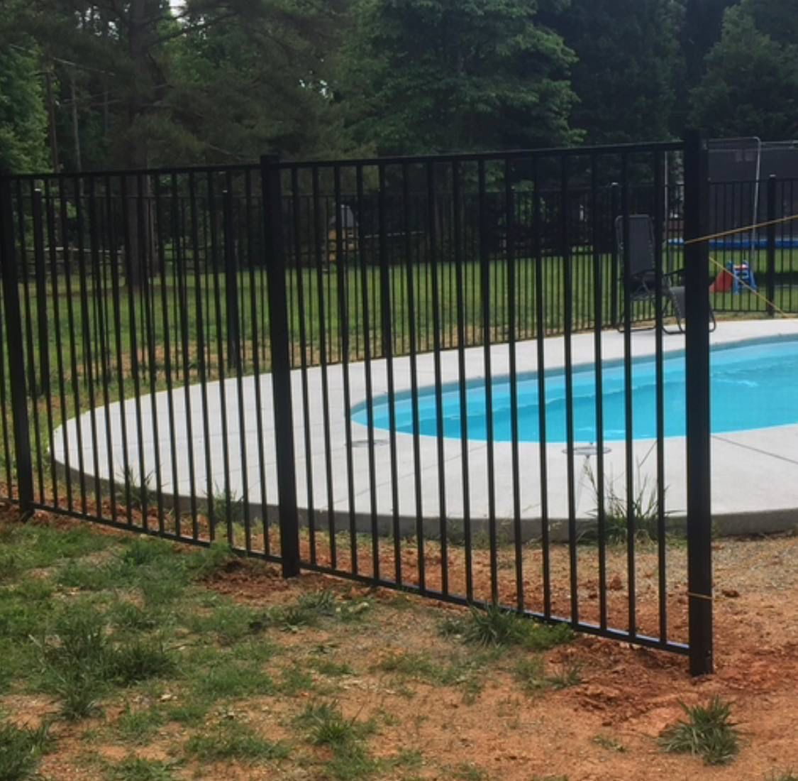 A black metal fence surrounds a swimming pool.