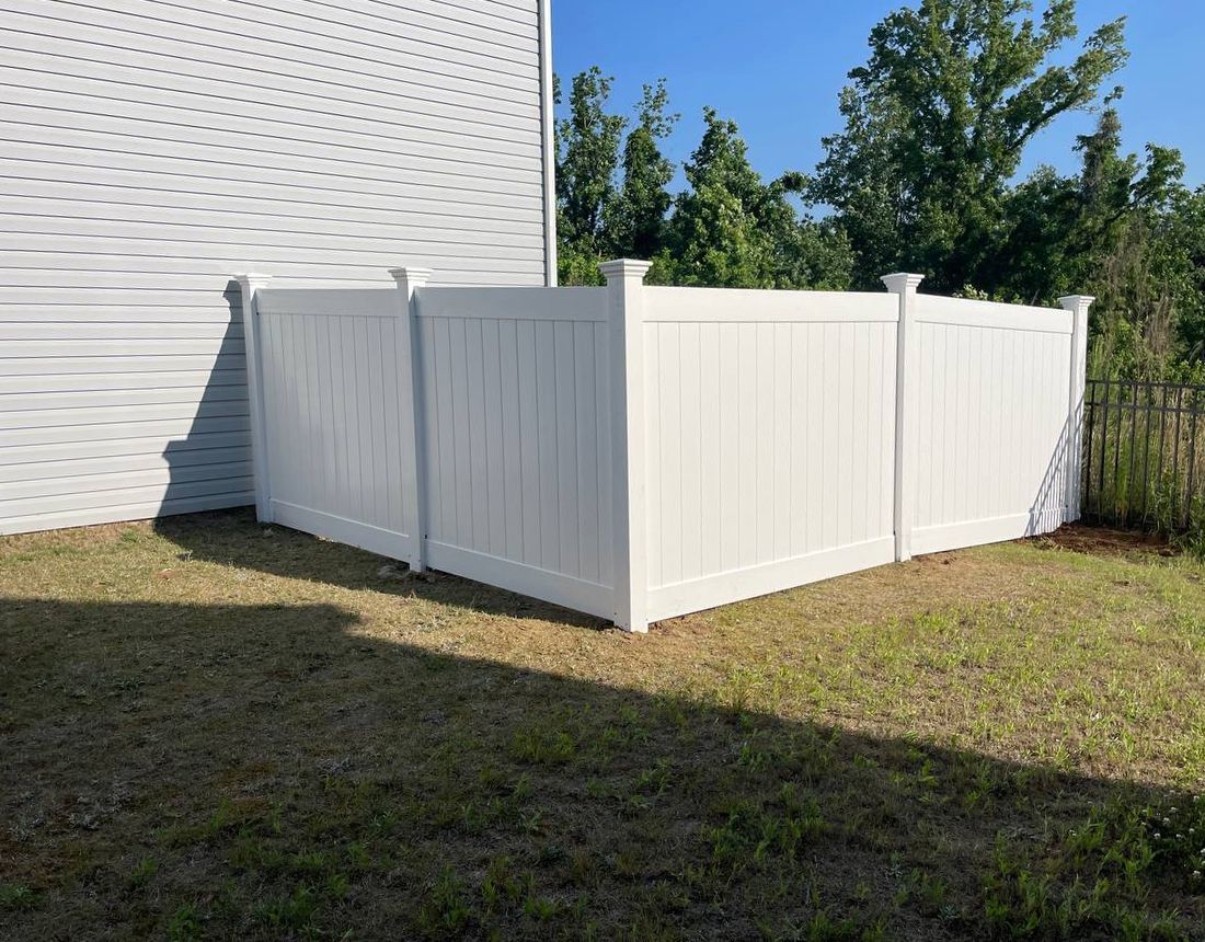 A white fence is in the backyard of a house.