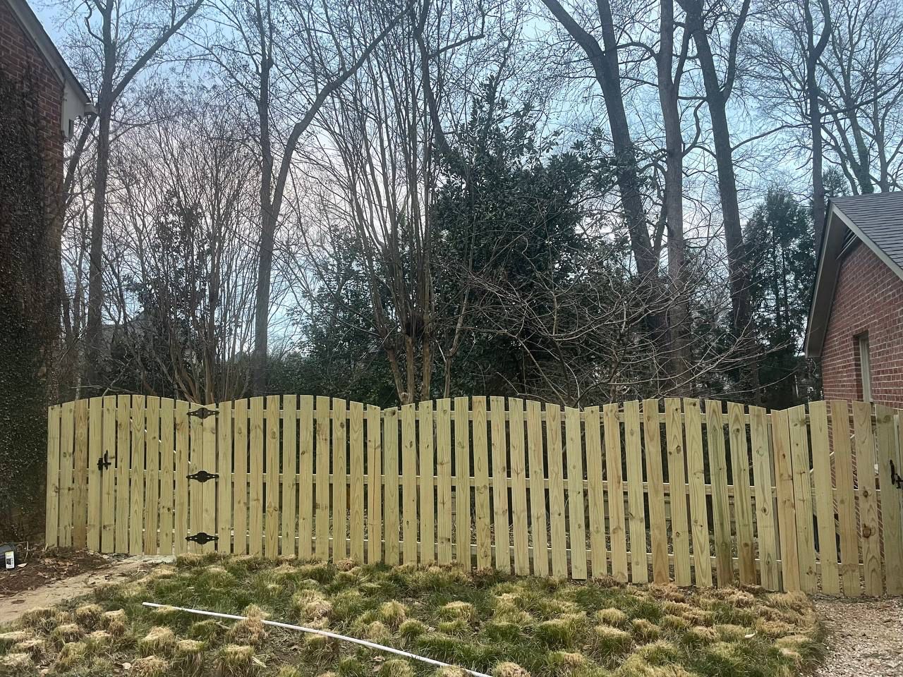 A wooden fence is surrounded by trees in a backyard.