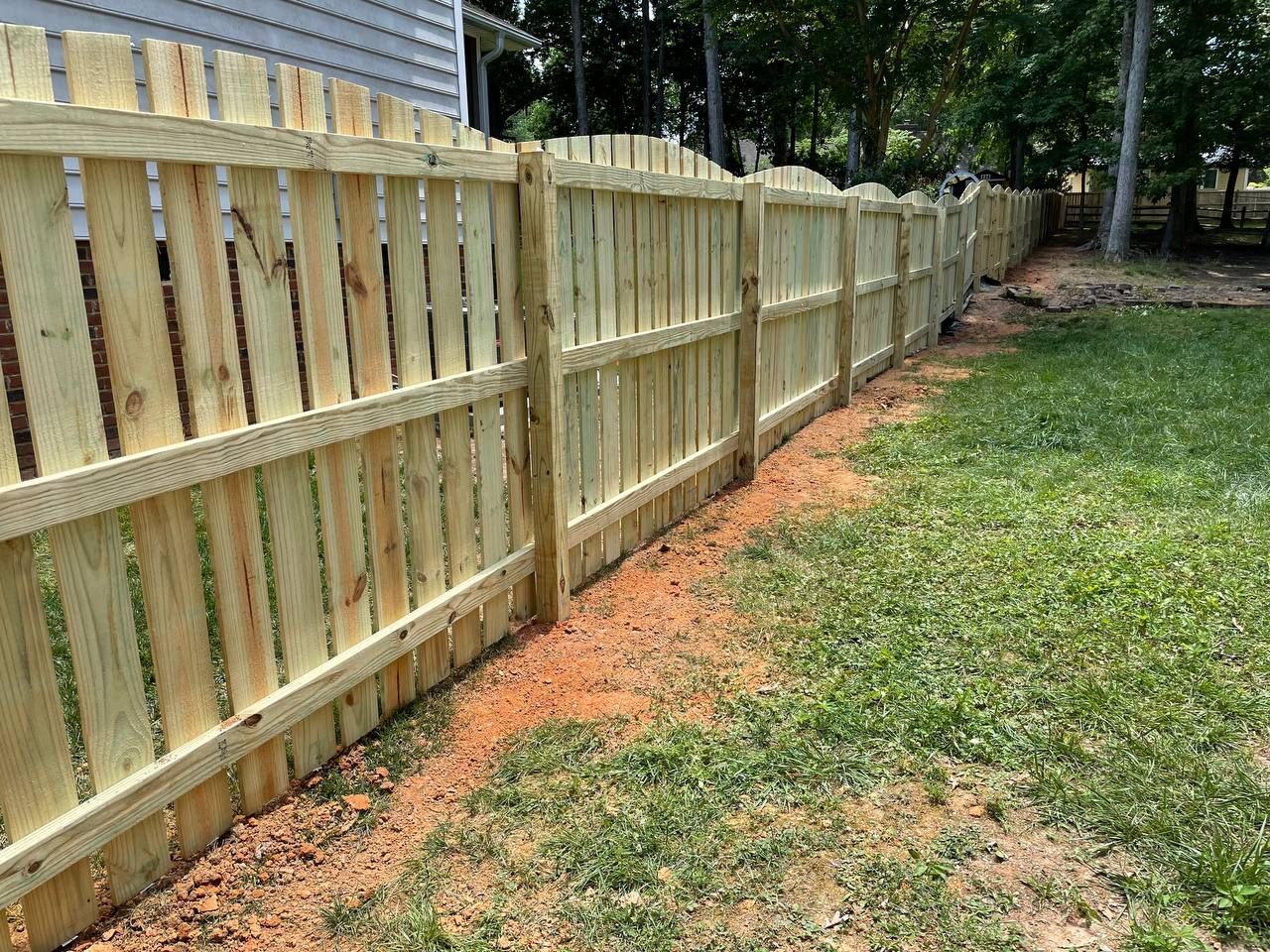 A wooden fence is sitting in the middle of a lush green yard.