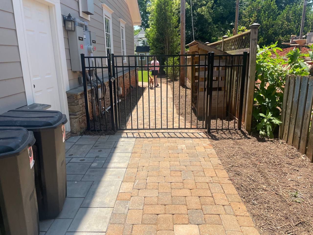 A brick walkway leading to a garage with a metal gate.