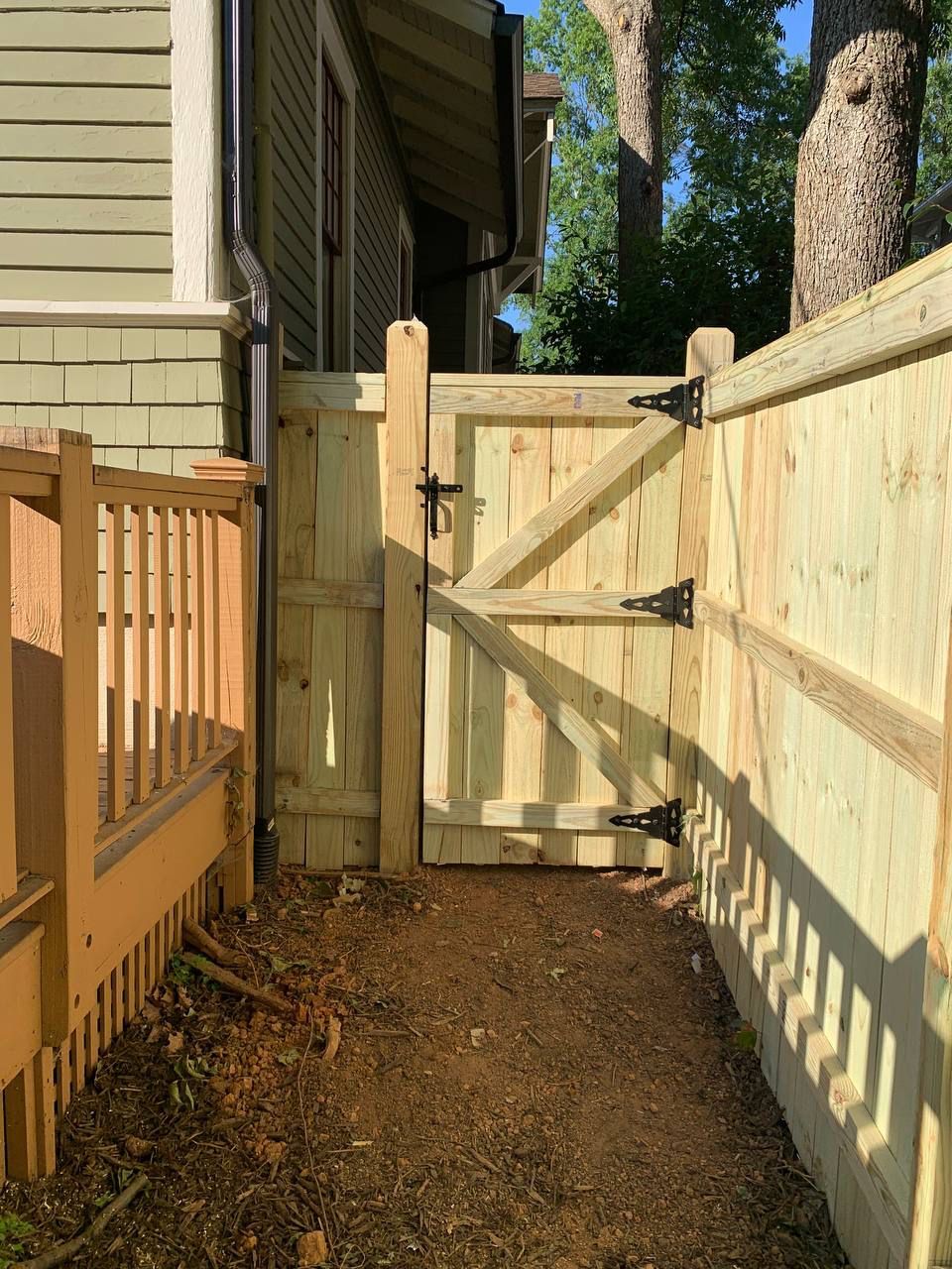 A wooden fence with a gate in the backyard of a house.