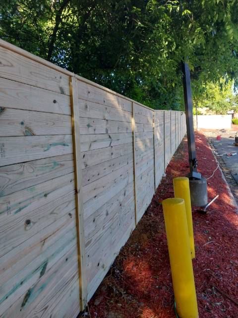 A wooden fence with yellow poles in front of it