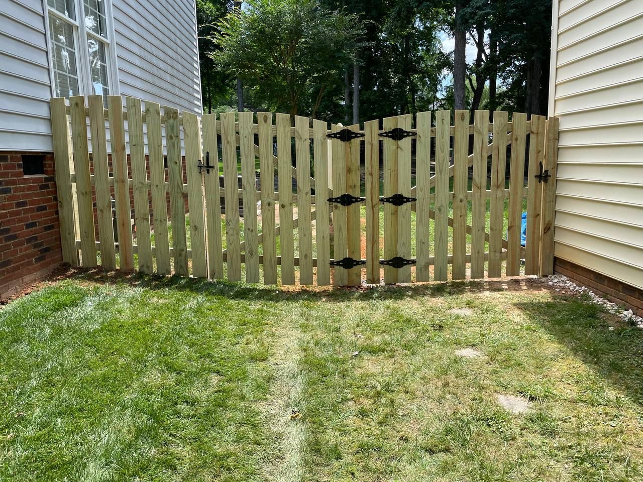 A wooden fence is in the backyard of a house.