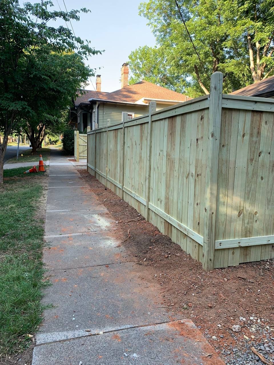 A wooden fence along a sidewalk next to a house