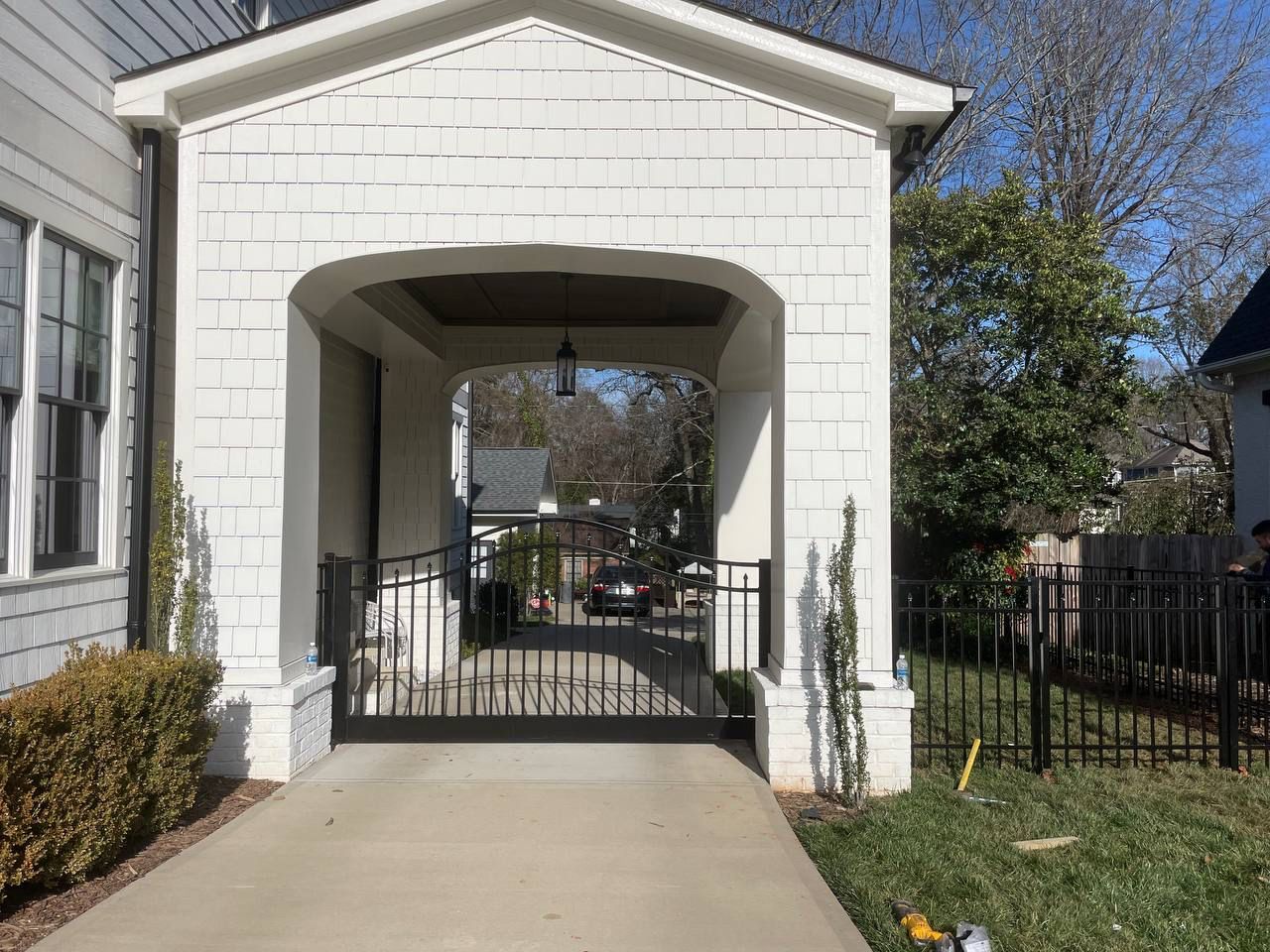 A white house with a porch and a driveway leading to it.