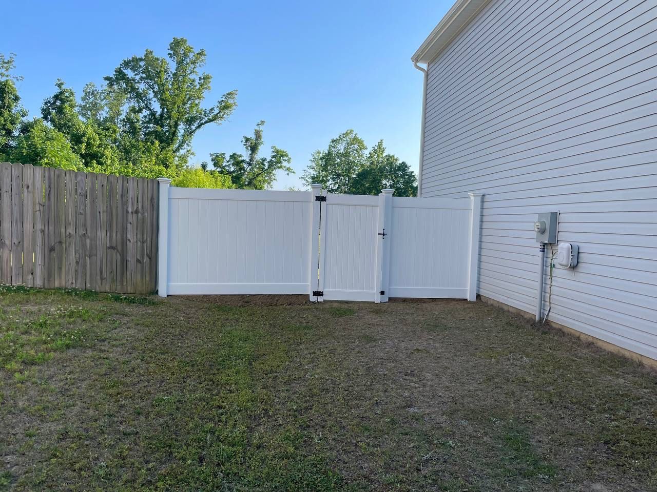 A white fence with a wooden fence behind it