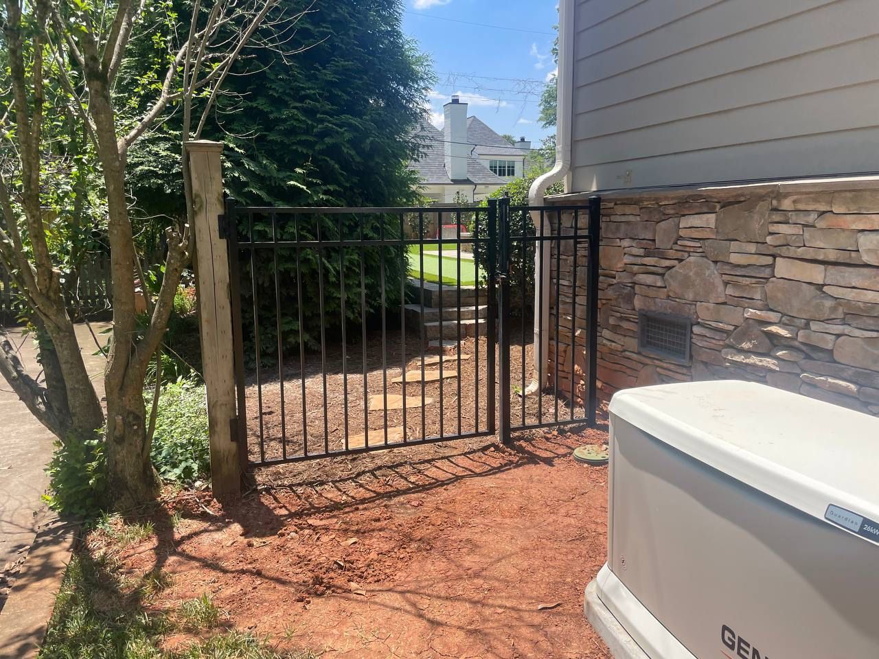 There is a generator in the backyard next to a gate.